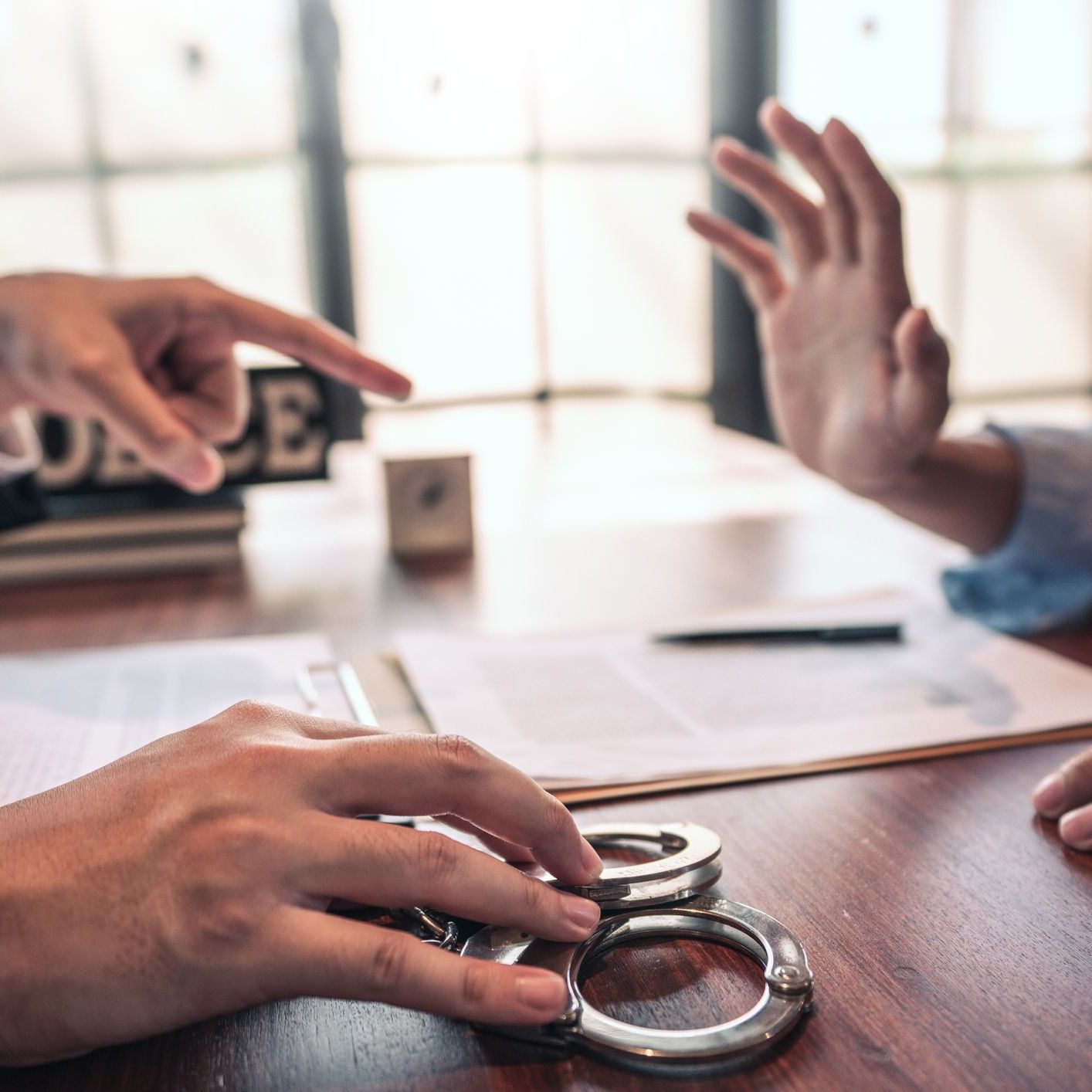 Police officer interrogating suspect or criminal man with handcuffs arrested at the investigation
